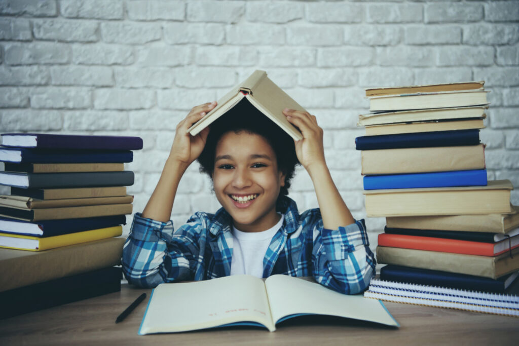 african-american-schoolboy-holds-book-head